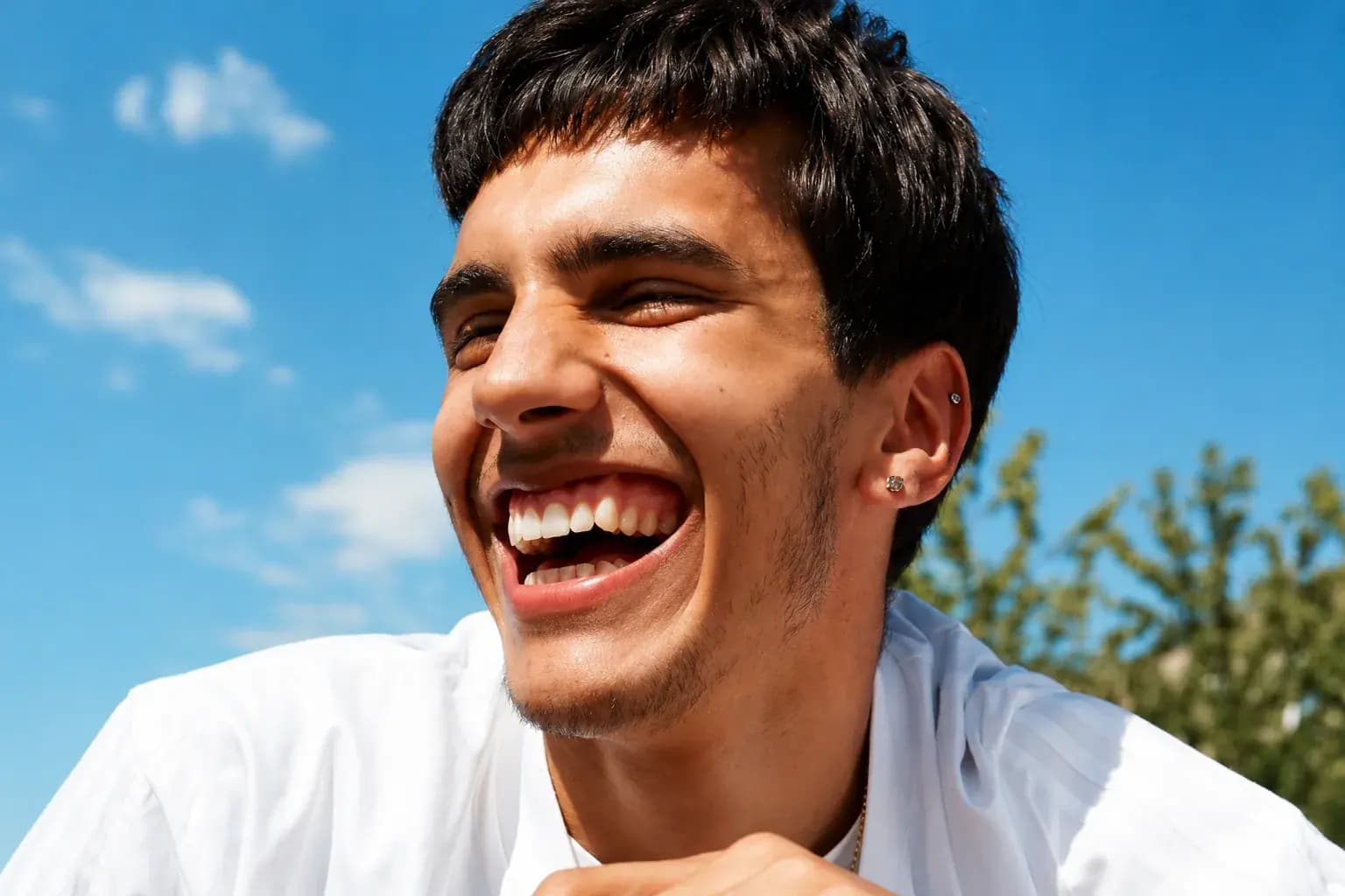 A young man laughing outdoors, photographed in black and white