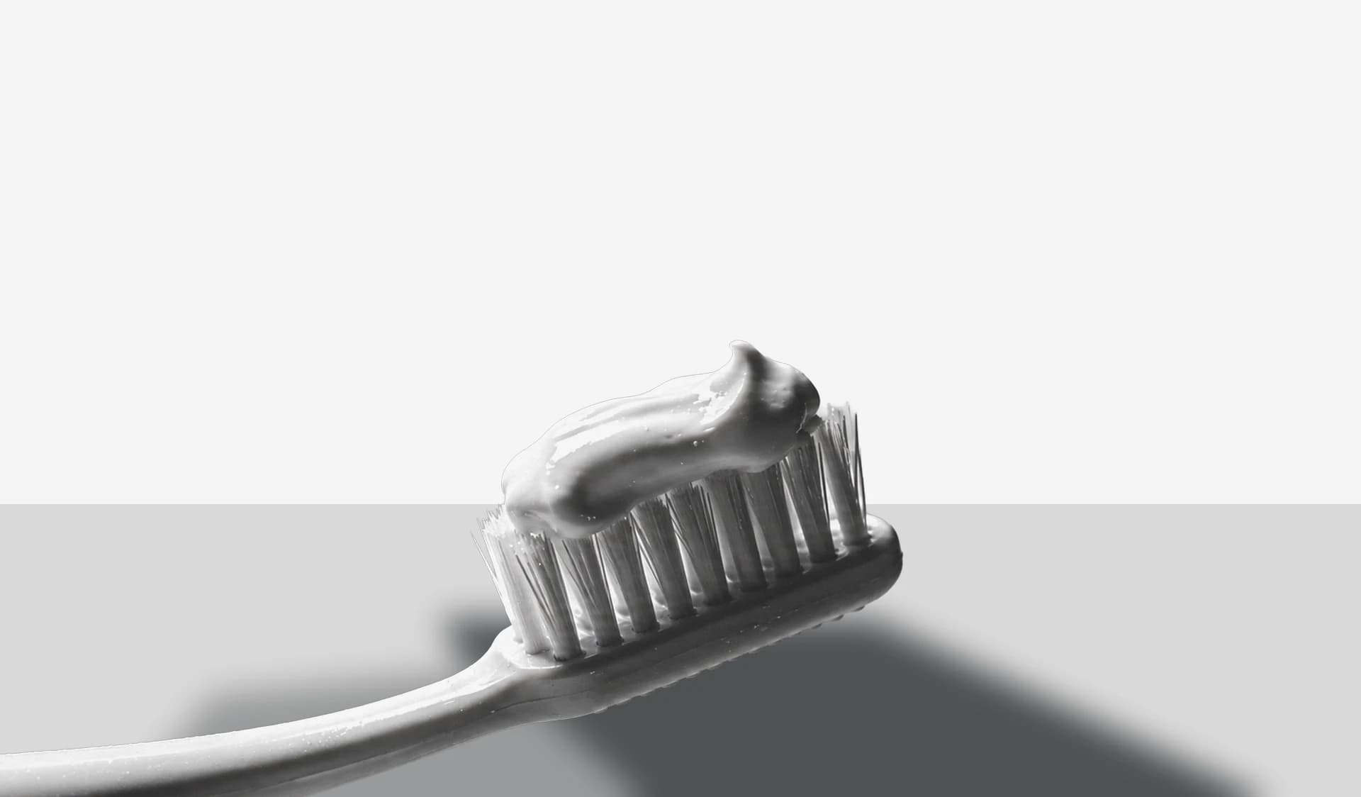A toothbrush loaded with toothpaste, lit from the side